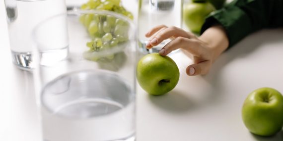 Refreshing image of green apples and grapes with glasses of water on a table, promoting healthy living.