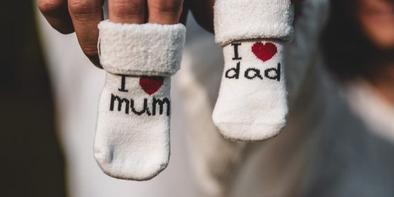 Adorable baby socks with 'I love mum' and 'I love dad' messages held by parents' hands. Perfect for family themes.